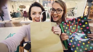 Bakış açısı selfie parlak kağıt poşet ve başparmak-up gösterilen ve komik surat alışveriş merkezinde alan genç kadın Öğrenciler bir kadeh. Shopaholics ve sevinç kavramı.
