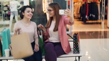 Modern Genç kadınlar smartphone alışveriş merkezi üzerinden online video çağrısı yapmak için kullanıyor. Kızlar sohbet ve gösteren gülen hazır giyim ve sallanan eller satın.