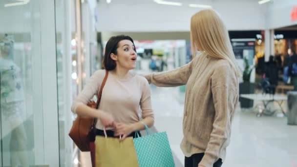 可愛い女の子は ショッピング モールで会合し 紙袋と議論の価格や衣類の購入を示します Shopaholism 現代青年のライフ スタイル コンセプト — ストック動画