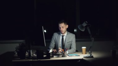 Yorgun adam ofis çalışanı bilgisayar üzerinde seyir yorgun ve bitkin gece toplantı belirlenen son tarihte geç saate kadar çalışıyor. Çalışkan gençlik, teknoloji ve stres kavramı.