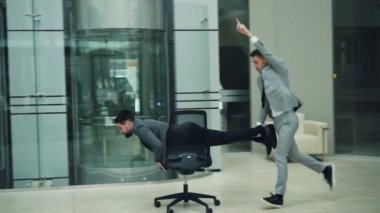 Heyecanlı gençler sakallı adamlar şık elbiseli ofis koltuğu ile lobisinde şirket partisinde eğleniyorlar. Komik etkinlik, millennials ve iş kavramı sevinç.