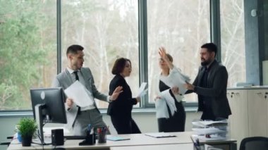 Neşeli arkadaşları grup şirket olay partide kutlama, kağıtları atma, gülen ve having fun ofiste dans ediyor. Gençlik, iş ve duygular kavramı.