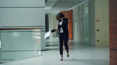 Kaygısız memur kağıt tutarak sonra klasör atmadan ve hareketli vücut rahatlatıcı lobisinde dans ediyor. Modern gençlik, iş insanlar ve eğlence kavramı.