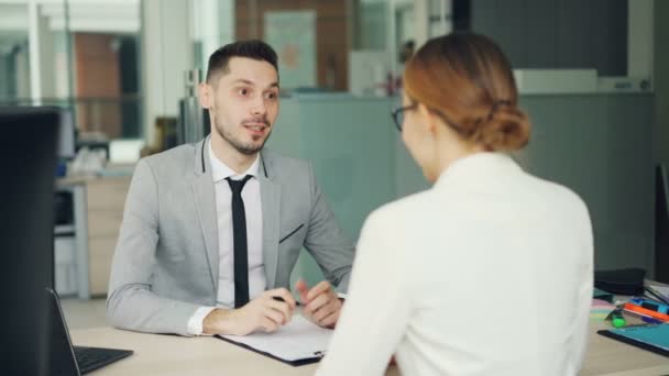 Χαμογελαστός νεαρός στρατολογών μιλάμε για νεαρή γυναίκα υποψήφιος τότε κουνώντας το χέρι κατά τη διάρκεια της συνέντευξη εργασίας στο γραφείο. Άτομα και εργασίες έννοια. — Αρχείο Βίντεο