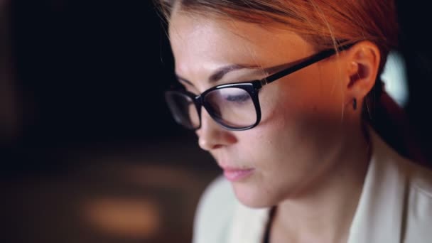 Imagen de la atractiva joven empresaria que trabaja hasta tarde en la noche solo en la oficina, un reflejo de la pantalla de la computadora es visible en sus gafas. Concepto de personas y trabajo . — Vídeos de Stock