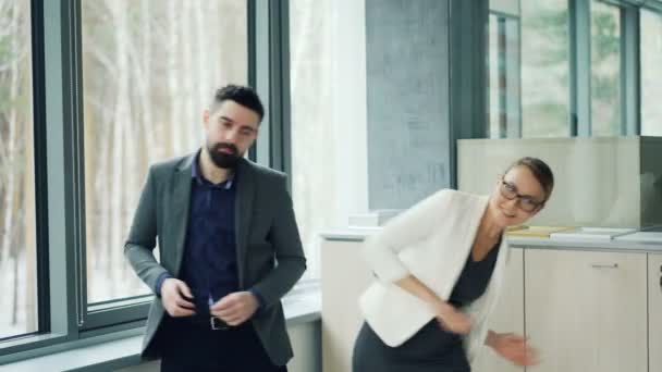 Schattig paar collega's man en vrouw dragen kostuums dansen in kantoor plezier samen genieten van de werkdag. Mensen, werk en feesten concept. — Stockvideo