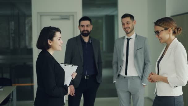 Pretty young woman is getting job in successful company shaking hands with CEO and smiling while other workers are clapping hands and expressing positive emotions. — Stock Video
