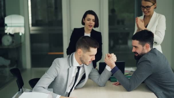 Trabalhadores de escritório de jovens barbudos estão se divertindo praticando braço wrestling enquanto as mulheres estão assistindo e apoiando-os, em seguida, fazendo high-five e palmas . — Vídeo de Stock