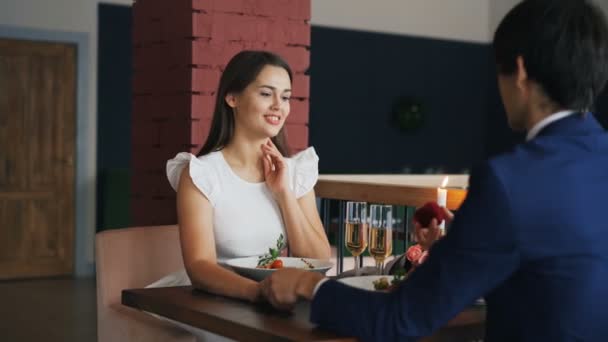 Loving young man is making proposal to his girlfriend in restaurant, girl is saying yes, boyfriend is giving her engagement ring and kissing hand. Marriage and dating concept. — Stock Video