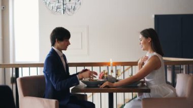 Evlenme teklifi genç adamı sevmek masada oturan ve ona el öpmeye bir yüzük hediye restoranı tarihte mutlu kız için yapıyor. Aile kurmak ve kavram dating.