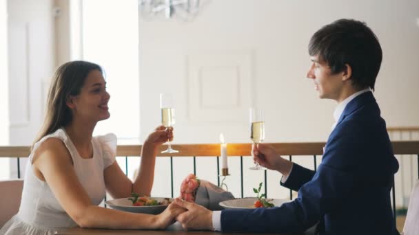 사랑 하는 젊은 사람 부딪치는 안경 그리고 레스토랑에서 낭만적인 날짜 동안 마시는 샴페인 유리를 들고 그의 약혼녀를 얘기입니다. 청소년과 데이트 개념. — 비디오