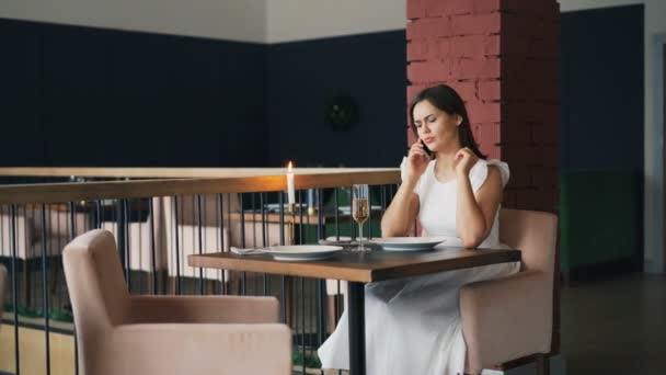 Hermosa chica en vestido blanco está esperando a su novio en el restaurante y luego llamarlo hablar con él enojado y salir. Citas, emociones negativas y concepto de personas . — Vídeos de Stock