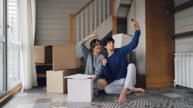 Genç ve güzel kadın ve kocası ile smartphone online video çağrısı tehcir sırasında yapıyoruz. Yeni evin anahtarları ve kutuları, söz ve gülümseyen gösteriyorsunuz.