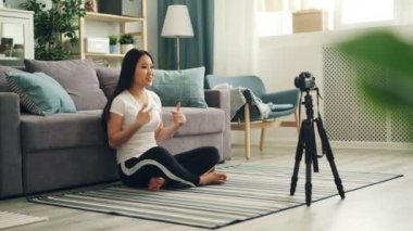 Neşeli Asyalı kadın popüler blogcu profesyonel kamera onun takipçileri için başparmak-up ve sallanan el gösterilen konuşmaya kullanarak video kayıt olduğunu. Vlogging ve teknoloji kavramı.