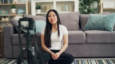Şirin Asyalı kız kadın blogger video kameraya bakıyor ve gülümsüyor ve gülüyor konuşurken onun Internet vlog kaydediyor. Bloglama ve teknoloji kavramı.