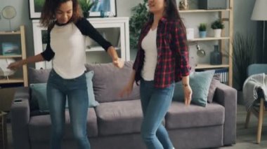 Modaya uygun kot pantolon şirin kızlar evde birlikte müzik ve having fun dans ediyor. Çok ırklı dostluk, modern yaşam tarzı ve tasasız gençlik kavramı.