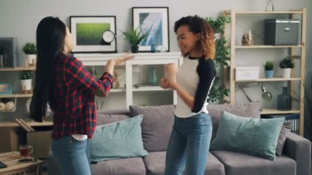 예쁜 젊은 여자 아시아, 아프리카계 미국인 음악을 듣고과 재미 함께 편안한 현대 아파트에서 집에서 춤 있다. 청소년과 여가 개념. — 비디오