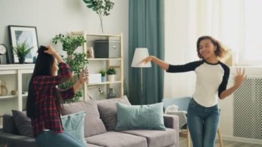 Duygusal Afro-Amerikan kız öğrenci, gülen ve having fun Asya arkadaşı smartphone kamera ile video kayıt sırasında evde dans ediyor. Gençlik ve teknoloji kavramı.