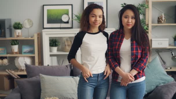 Portrait of beautiful young women Asian and African American standing at home together, looking at camera and smiling. People are wearing casual clothing. — Stock Video