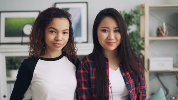漂亮学生的慢镜头, 混血朋友亚洲人和非洲裔美国人看着相机, 微笑着站在家里的室内. — 图库视频影像