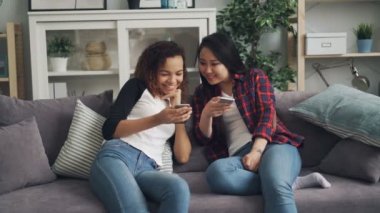 Gülümseyen genç kadınlar konuşmaya ve ekran zevk sosyal medya ve modern teknolojiler bakarak gülen smartphones kullanıyorsunuz. İletişim ve gençlik kavramı.