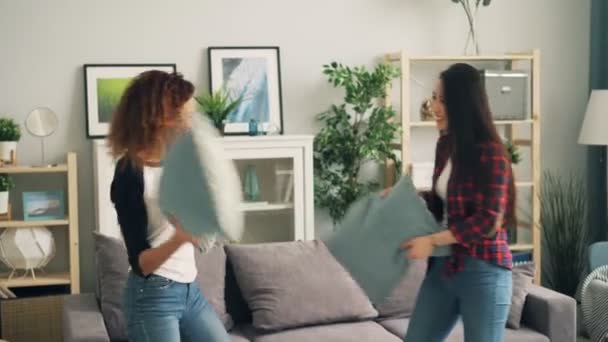 Vonzó lányok, ázsiai és afrikai-amerikai élvezik párna küzdelem otthoni szórakozás közben szabad idő. Ifjúsági életstílus, a többnemzetiségű barátság és a házak koncepció. — Stock videók