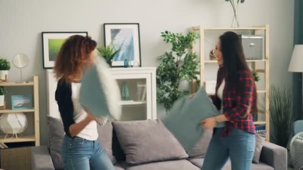 Chicas atractivas Asiático y afroamericano están disfrutando de la pelea de almohadas en casa divertirse durante el tiempo libre. Estilo de vida juvenil, amistad multirracial y concepto de casas . — Vídeos de Stock