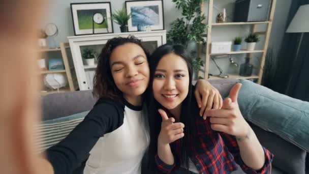 Oogpunt schot van aantrekkelijke jonge dames Afro-Amerikaanse en Aziatische nemen selfie thuis poseren voor de camera en scherm aan te raken. Foto en jeugd concept. — Stockvideo