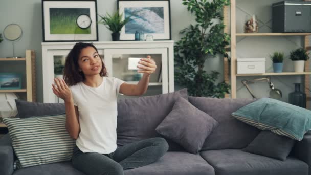 Jeune femme afro-américaine appelle des amis sur skype faire un appel vidéo en ligne avec smartphone parler et montrer son nouvel appartement avec intérieur cool . — Video