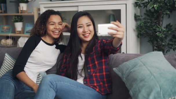 Un par de amigos están haciendo videollamadas en línea con dispositivo de retención de teléfonos inteligentes, mirando a la pantalla, hablando y haciendo gestos. Gente, artilugios y concepto juvenil . — Vídeos de Stock