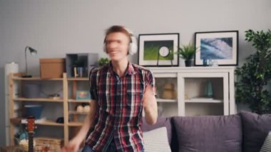 Yakışıklı hipster eğlenceli evde boş vaktinizi şarkı ve dans kulaklık ile müzik dairede yaşıyor. Gençlik yaşam tarzı ve ev kavramı.