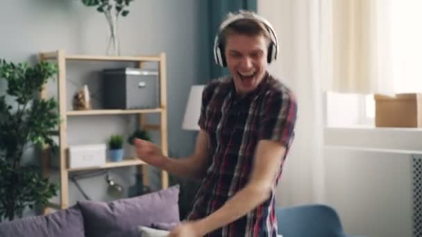 Glad kille njuter låt i hörlurar dansande och sjungande lyssna på popmusik avkopplande och ha roligt. Millennials, prylar och livsstil koncept. — Stockvideo