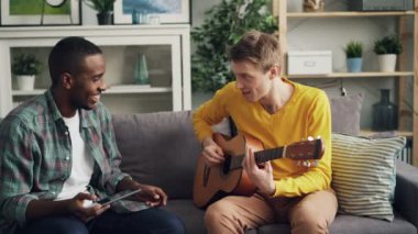 Mutlu çocuklar Afrikalı-Amerikalı ve Kafkas gülüyor ve iyi bir şirket, müzik ve yeni deneyim zevk beşlik yapıyor o zaman tablet kullanarak gitar çalmayı öğrenme.