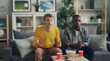 Neşeli erkek öğrencilerin spor oyunu favori takım destekleyen TV izliyor sonra zafer alkışlar kutlama dans ve eğlence gülüyor eller.