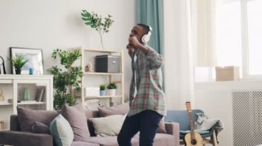 Yakışıklı olan Afro-Amerikan dans ve ışık düz kulaklık üzerinden müzik şarkı. Adam rahat giyim kot pantolon ve gömlek giyiyor.