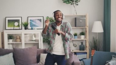 Yaratıcı Afrikalı-Amerikalı adam uzaktan kumandaya şarkı ve Kulaklığımda güzel ışık daire rahatlatıcı müzik dans. Gençlik, yaşam tarzı ve kültür kavramı.