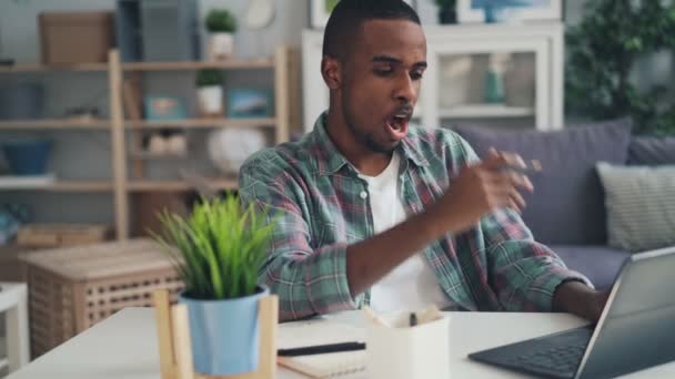 Slaperig, moe en gestresst freelance werknemer Afrikaanse Amerikaanse jongen is met behulp van laptop thuis werken en geeuwen gevoel van vermoeidheid. Millennials en harde werk concept. — Stockvideo