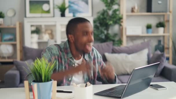 Gelukkig freelancer werkt thuis met laptop dan lachen en gebaren van positieve emoties espressing genieten van zijn prestaties. Moderne technologie en succes concept. — Stockvideo