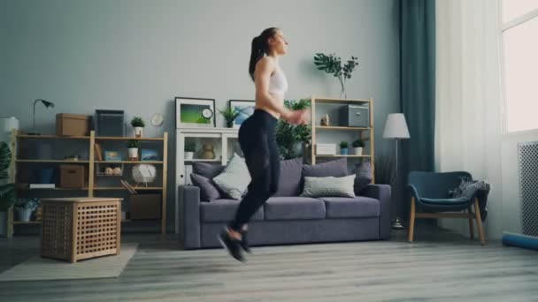 Slanke jonge dame gericht op het draaien op de plek te oefenen in het licht appartement. — Stockvideo