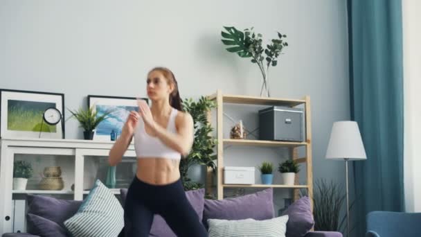 穿着运动服装的瘦身妇女在家锻炼举起手臂和蹲着. — 图库视频影像