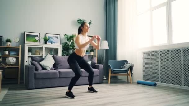 Vonzó fiatal nő guggolva otthon csinál gyakorlatokat súlycsökkenés. — Stock videók