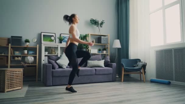 Giovane donna sportiva che corre sul posto a casa esercitandosi godendo di attività . — Video Stock