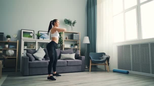 Starke Studentin hockt zu Hause auf dem Boden und konzentriert sich auf Sport. — Stockvideo