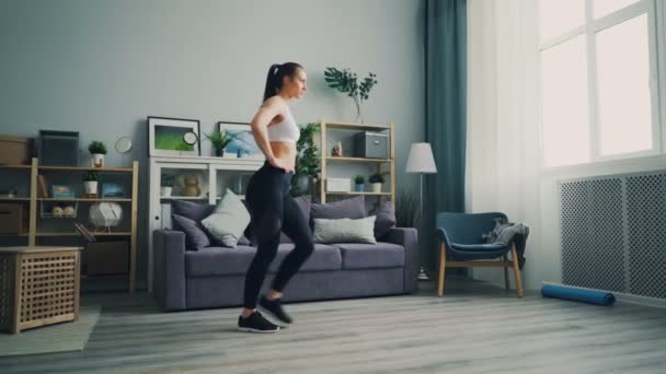 Estudante muito feminino fazendo esportes em casa agachado desfrutando de um estilo de vida saudável — Vídeo de Stock