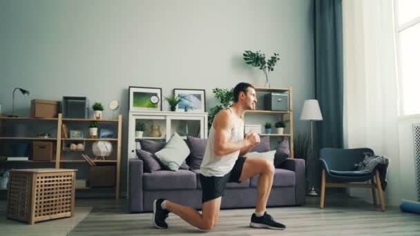 Snygg idrotts utövare i snygga kläder gör fysiska övningar hemma. — Stockvideo