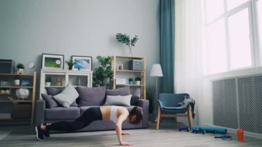 Fit kadın öğrenci evde egzersiz yaparken şınav ve atlama kilo kaybetme