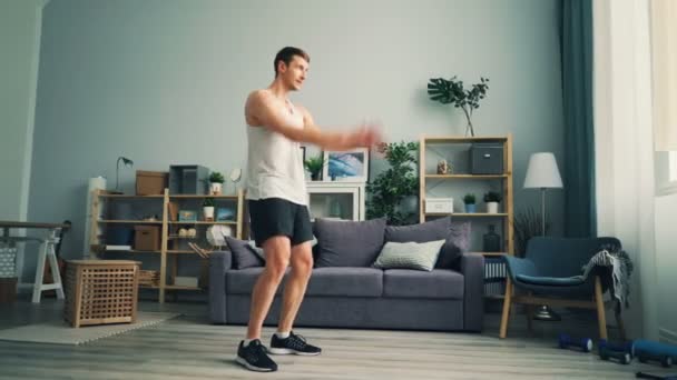 Активный спортсмен, занимающийся на дому вращающимися руками, делая упражнения для плеч — стоковое видео
