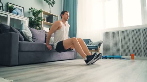 Male student doing push-up dips with sofa at home using couch for bodybuilding — Stock Video