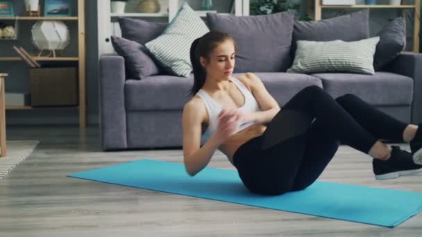 Sportig ung kvinna gör ABS övningar rörliga kropp på yoga matta i lägenheten. — Stockvideo