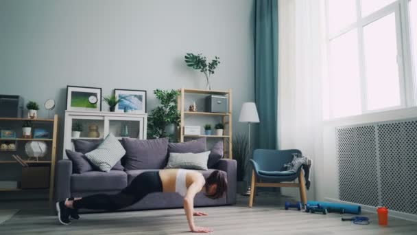 Ajuste estudiante femenina haciendo ejercicio en casa haciendo flexiones y saltando perdiendo peso — Vídeos de Stock